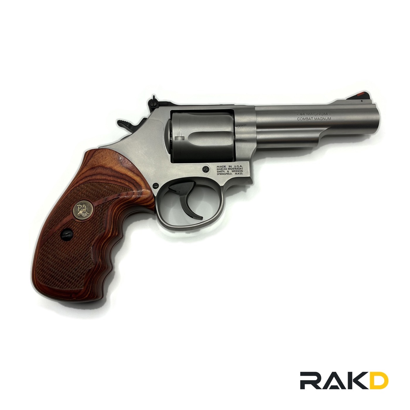 A stainless Smith & Wesson revolver with a four inch barrel and figured wood target grips, the barrel marked 44 Magnum Combat Magnum, and a red ramp front sight.